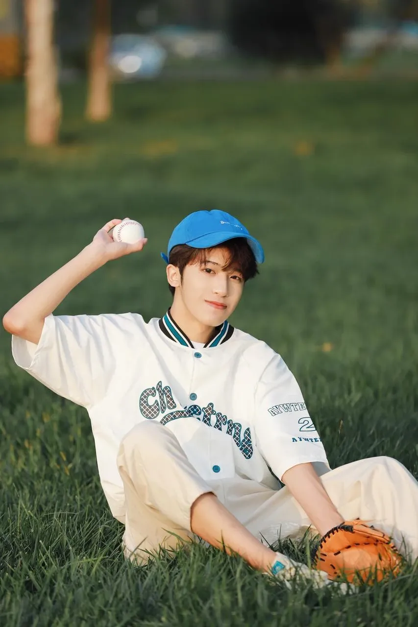 a baseball boy sit on the grass