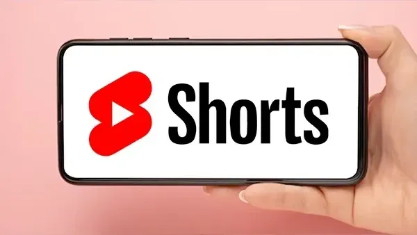 YouTube Shorts logo displayed on a smartphone held in hand